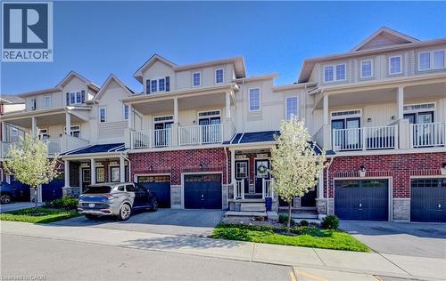Townhome exterior featuring brick and siding facade, private balconies with white railings, integrated garages, and covered front entryways - 403 Westwood Drive Unit# 59, Kitchener, ON 