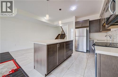 Open-concept kitchen with a central island, light-toned tile flooring, and dark wood-finish cabinetry - 403 Westwood Drive Unit# 59, Kitchener, ON 