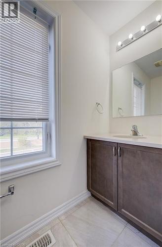 Bathroom featuring a large window, tiled flooring, wood-finish vanity with dual doors, light-toned countertop, and an illuminated mirror - 403 Westwood Drive Unit# 59, Kitchener, ON 