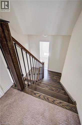 Staircase featuring wood-finish treads, iron balusters, and a rich wood-finish handrail - 403 Westwood Drive Unit# 59, Kitchener, ON 