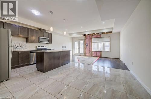 Kitchen featuring dark wood-finish cabinetry, stainless steel appliances, a white countertop, and a kitchen island - 403 Westwood Drive Unit# 59, Kitchener, ON 