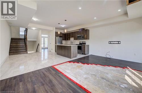 Modern kitchen featuring dark wood-finish cabinetry, stainless steel appliances, and a central island with countertop seating - 403 Westwood Drive Unit# 59, Kitchener, ON 