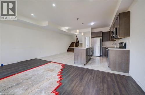 Kitchen featuring a central island with a light-colored countertop, dark wood-finish cabinetry, stainless steel appliances, and light-colored tile flooring - 403 Westwood Drive Unit# 59, Kitchener, ON 