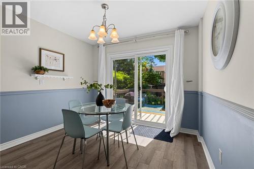 Wood-finish flooring, two-tone painted walls with chair rail, built-in wall shelf, ceiling-mounted chandelier, and sliding glass door leading to an outdoor deck - 1610 Heathside Crescent, Pickering, ON 