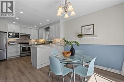 Integrated kitchen and dining area featuring light-toned cabinetry, stainless steel appliances, and wood-finish flooring - 
