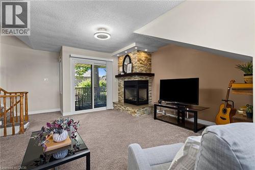 Carpeted interior featuring a stone-clad fireplace with a dark wood mantel, a sliding glass door to an outdoor space, and a wooden stair railing - 1610 Heathside Crescent, Pickering, ON 