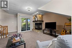 Carpeted interior featuring a stone-clad fireplace with a dark wood mantel, a sliding glass door to an outdoor space, and a wooden stair railing - 