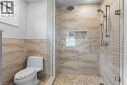 Glass-enclosed shower with a rainfall showerhead, handheld shower fixture, and a recessed niche - 