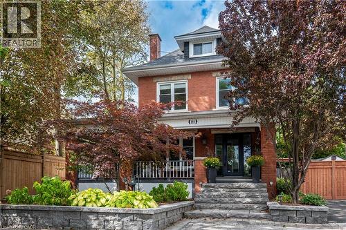 Brick exterior with white trim, dark shingle roof, and a red brick chimney - 283 Plains Road W, Burlington, ON 