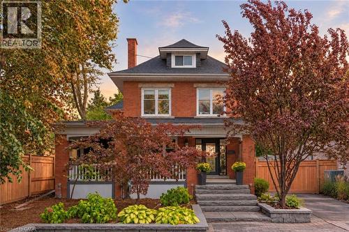 Red brick exterior with a dark shingle roof and white trim - 283 Plains Road W, Burlington, ON 