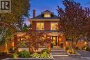 Brick exterior with a prominent front entrance, featuring a covered porch with white railing, and a gabled dormer - 283 Plains Road W, Burlington, ON 