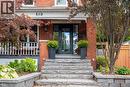 Brick exterior with a prominent front entrance, stone steps, and a landscaped garden with mature trees - 283 Plains Road W, Burlington, ON 