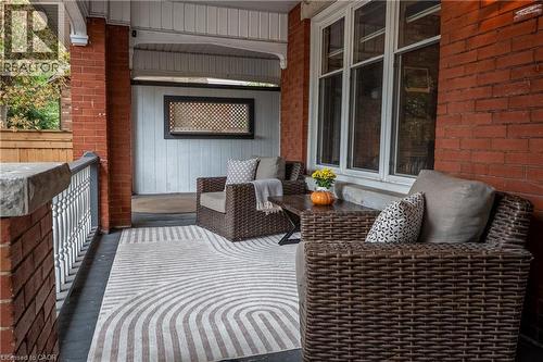 Covered front porch featuring brick columns, white balusters, and a lattice detail - 283 Plains Road W, Burlington, ON 