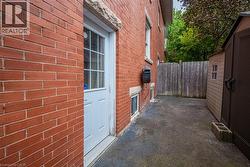 Red brick exterior with a white paneled door, offering access to a paved side yard - 