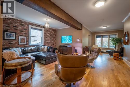 Exposed brick accent wall, wood-finish flooring, exposed ceiling beams, recessed lighting, and large windows - 283 Plains Road W, Burlington, ON 