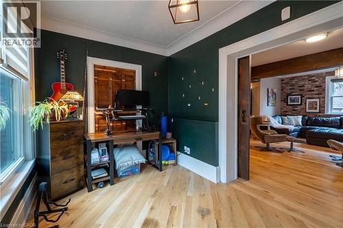Hardwood flooring throughout, with a dark green wall finish, white trim, and a sliding barn door - 283 Plains Road W, Burlington, ON 