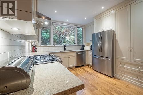 Kitchen featuring wood-finish flooring, recessed lighting, white subway tile backsplash, and stainless steel appliances - 283 Plains Road W, Burlington, ON 