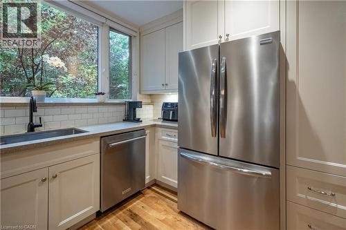 Stainless steel appliances, light-toned cabinetry, light-toned countertops, subway tile backsplash, and wood-finish flooring - 283 Plains Road W, Burlington, ON 