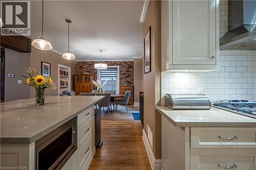 Kitchen featuring light-toned countertops, white subway tile backsplash, stainless steel range hood, and pendant lighting - 283 Plains Road W, Burlington, ON 