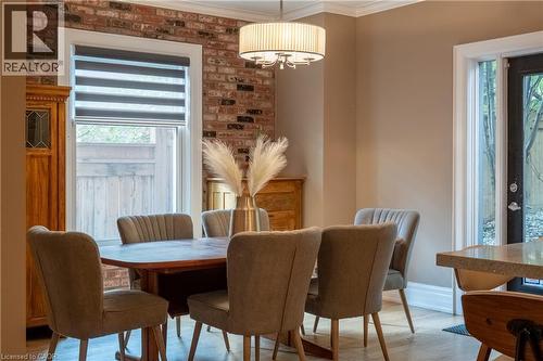 Exposed brick accent wall, crown molding, drum pendant light fixture, and wood-finish flooring - 283 Plains Road W, Burlington, ON 