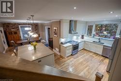 Open-concept kitchen and dining area featuring light wood-finish flooring, a kitchen island with a light-toned countertop, white cabinetry, and stainless steel appliances - 