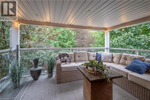 Covered outdoor living space with a slatted ceiling, glass panel railing, and recessed lighting - 283 Plains Road W, Burlington, ON 
