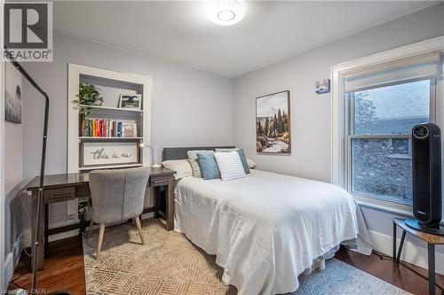 Recessed built-in shelving, wood-finish flooring, white trim, and a window with roller shade - 283 Plains Road W, Burlington, ON 