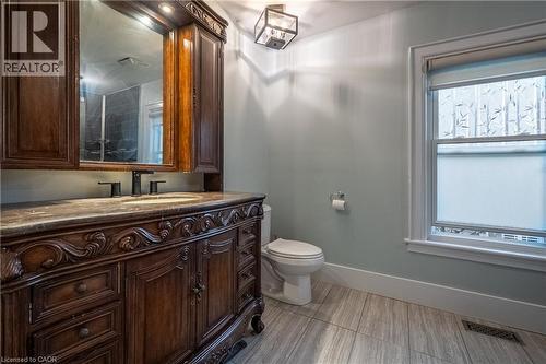 Ornate wood vanity with a stone countertop and integrated sink - 283 Plains Road W, Burlington, ON 