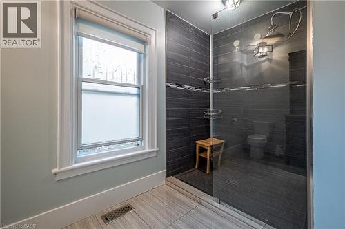 Walk-in shower with clear glass enclosure, dark-toned tile surround, and a rain showerhead - 283 Plains Road W, Burlington, ON 