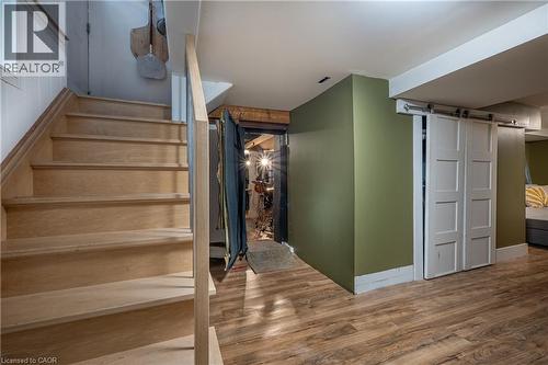 Wood-finish flooring, staircase with wood treads and railing, and sliding barn doors - 283 Plains Road W, Burlington, ON 