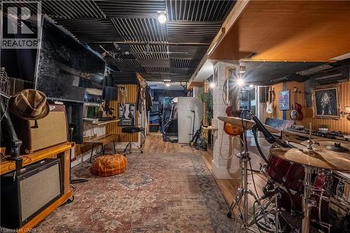 Wood-finish flooring, acoustic panel ceiling, wood paneling, recessed lighting, and wall-mounted shelving - 283 Plains Road W, Burlington, ON 