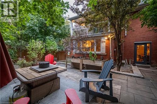 Stone patio with extensive plantings, raised garden beds, and mature trees - 283 Plains Road W, Burlington, ON 