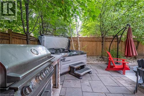 Patio with stone pavers, built-in grill station, and an outdoor spa - 283 Plains Road W, Burlington, ON 