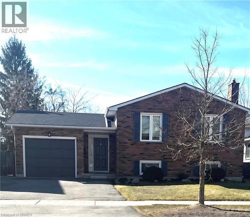 Split level home with a garage, brick siding, a chimney, driveway, and a front lawn - 104 Viscount Road, Brantford, ON 