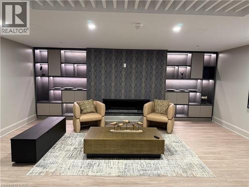 Integrated built-in shelving with accent lighting, central fireplace with patterned wall treatment, wood-finish flooring, and white ceiling with decorative slats - 10 Mallard Trail Unit# 237, Waterdown, ON 