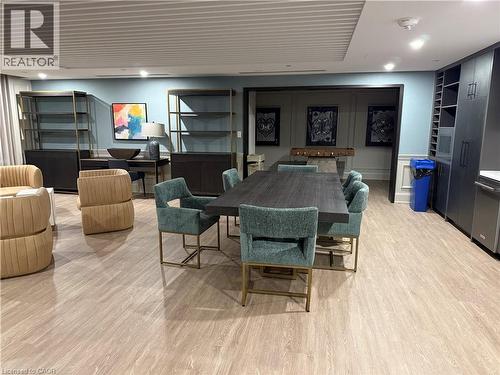 Wood-finish flooring throughout, featuring a recessed ceiling with integrated lighting, built-in shelving, and dark-toned cabinetry with integrated appliances - 10 Mallard Trail Unit# 237, Waterdown, ON 