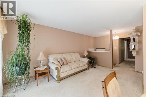 Carpeted living area with neutral wall tones, a partial wall separation, and a chandelier fixture - 450 Brigadoon Drive, Hamilton, ON 
