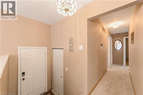 Entry foyer featuring a vaulted ceiling with chandelier, paneled entry door with smart lock, and an adjacent storage closet - 450 Brigadoon Drive, Hamilton, ON 