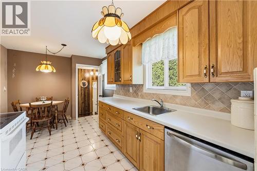 Kitchen featuring breakfast nook, natural wood cabinetry, light-toned countertops, and a stainless steel dishwasher, stairs off to the side for separate side entrance - 450 Brigadoon Drive, Hamilton, ON 