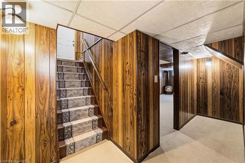 Staircase leading to basement, carpeted runner, landing and hallway leading to recreation room with a door, to the right side is a small cold cellar - 450 Brigadoon Drive, Hamilton, ON 