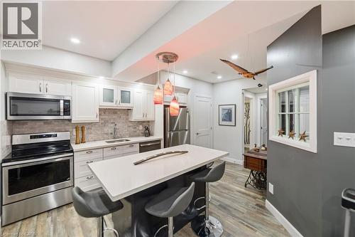 In-law kitchen featuring stainless steel appliances, over the range microwave, dishwasher, fridge and stove.  Stacked laundry is to the left of the stove, full size pantry - 515 Hamilton Drive, Ancaster, ON 