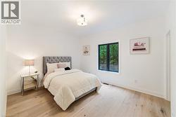 Bedroom featuring luxury flooring, large window looking onto greenspace and custom cabinetry in walk-in closet - 