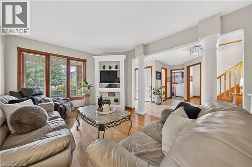 Spacious living area featuring wood-finish flooring, a built-in media cabinet, and large windows with wood trim - 52 Archwood Crescent, Cambridge, ON 