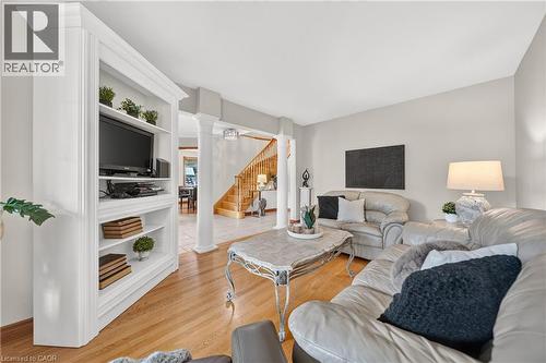 Built-in white media shelving with crown molding, light wood-finish flooring, white architectural columns, a light-toned ceiling, and neutral wall tones - 52 Archwood Crescent, Cambridge, ON 