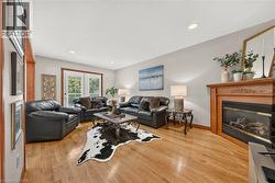 Hardwood flooring, corner fireplace with wood mantel, recessed lighting, and white French doors - 