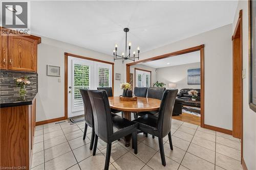 Tile flooring with a dark grout, wood cabinetry, dark countertops, and a mosaic tile backsplash - 52 Archwood Crescent, Cambridge, ON 