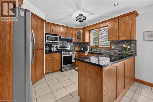 Kitchen featuring wood cabinetry, stainless steel appliances, dark countertops, a tiled backsplash, and recessed lighting - 52 Archwood Crescent, Cambridge, ON 