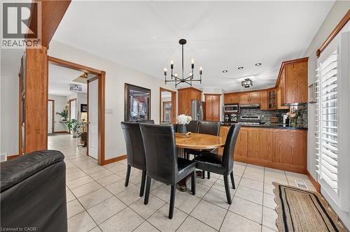 Integrated kitchen and dining area featuring ceramic tile flooring, wood cabinetry, built-in stainless steel appliances, and ceiling-mounted lighting - 52 Archwood Crescent, Cambridge, ON 