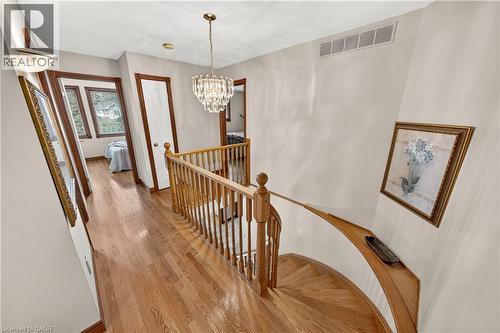 Hardwood flooring, wood spindle railing, crystal chandelier, wall-mounted light fixtures, and white paneled doors with wood trim - 52 Archwood Crescent, Cambridge, ON 