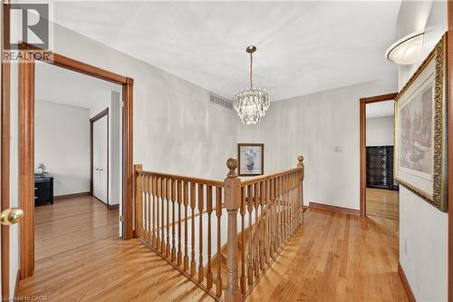 Hardwood flooring, wood staircase with balusters, crystal chandelier, and white walls - 52 Archwood Crescent, Cambridge, ON 